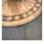 Eine art Kompassrose aus Kupfer auf der Veritas steht. Diese ist angeschnitten und nimmt den Platz oben und links im Bild ein.