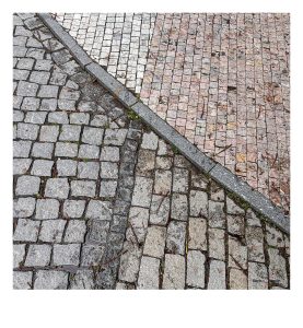 4 verschiedene Arten von Pflastersteinen, getrennt durch eine Bordsteinkannte die in einem Bogen, schräg durch das Bild läuft. 